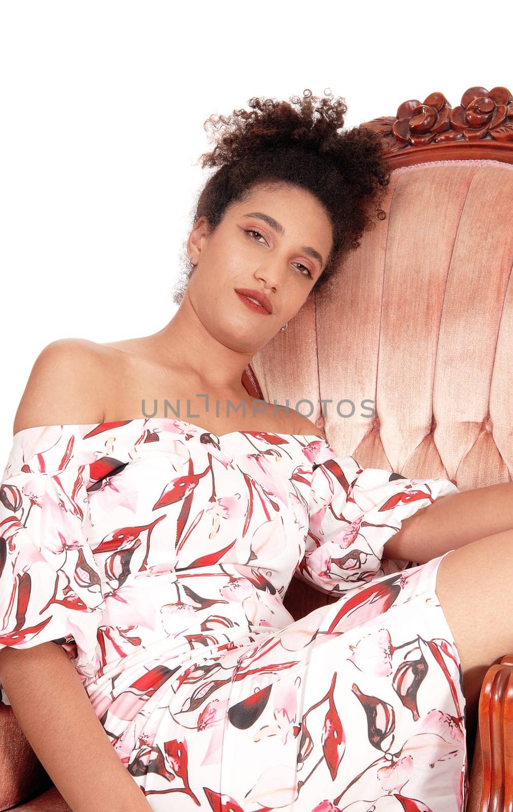 A gorgeous multi-racial woman sitting in a summer dress in an old.armchair dreaming, with her curly black hair, isolated.for white background.