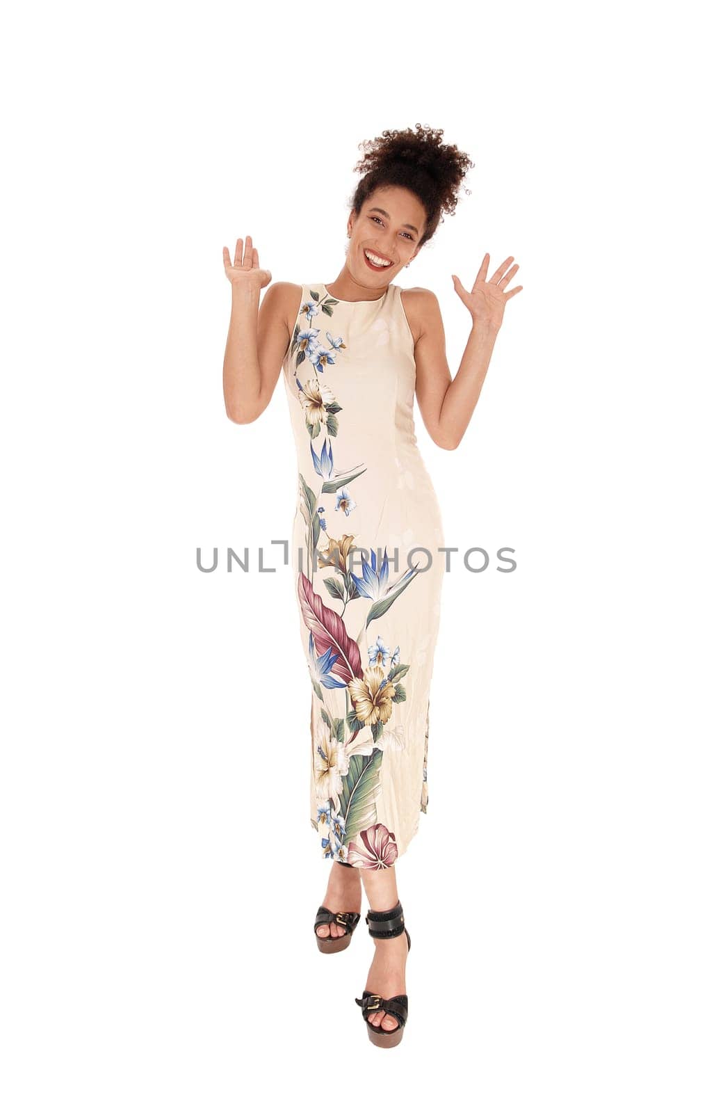 A gorgeous young multi-racial woman standing in a long summer dress.and heels, looking into the camera with her black.curly hair in a bun, isolated for white background.