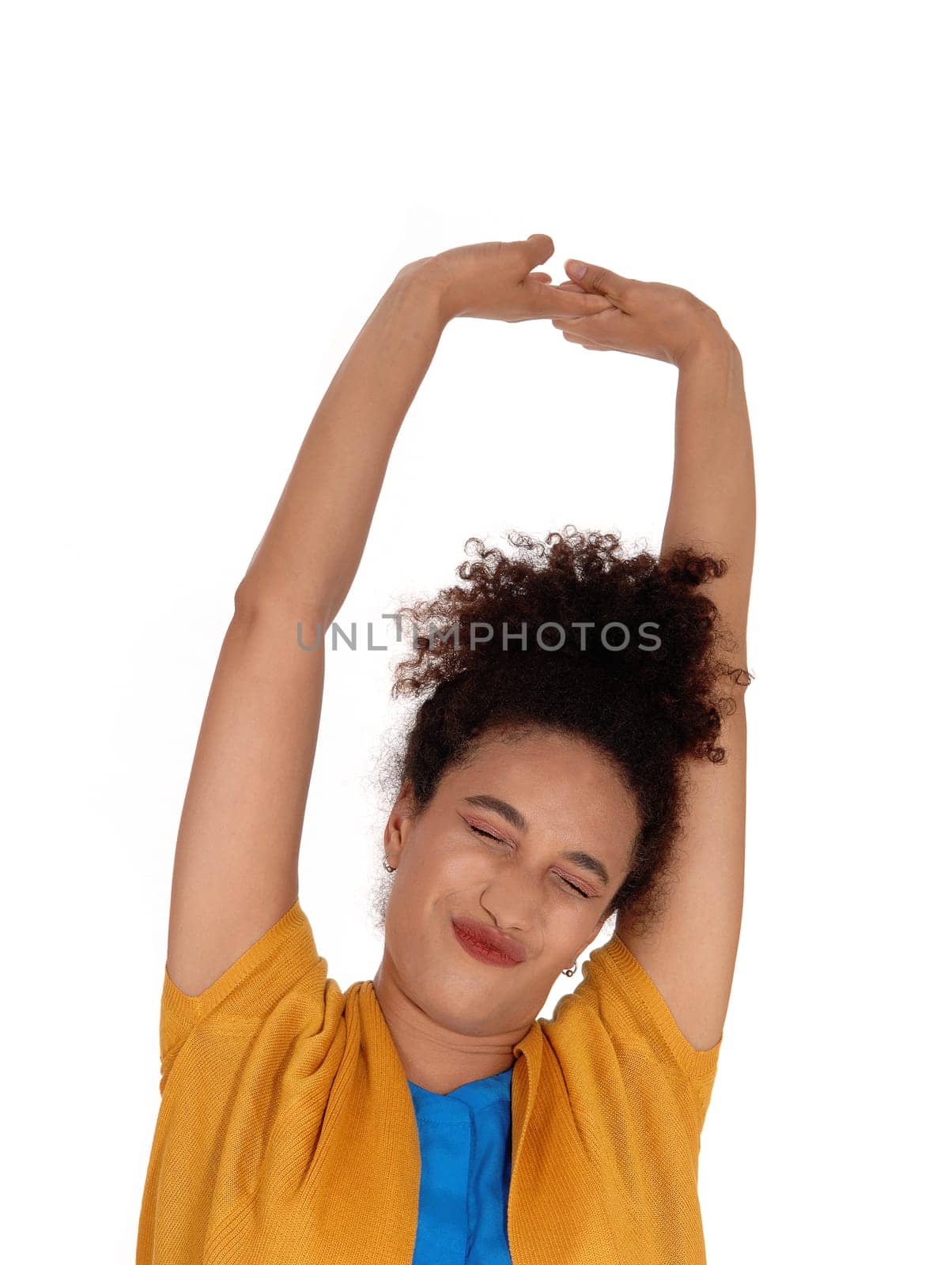 A beautiful multi-racial woman in sweater standing on the .floor, stretching her arms up with closed eyes, isolated for white.background.