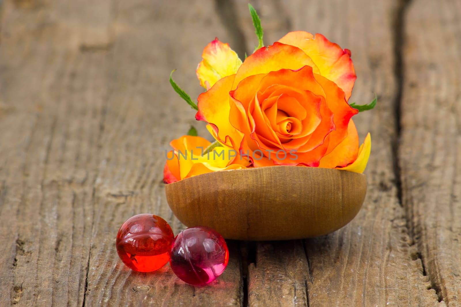 rose and oil bath pearls on wooden background