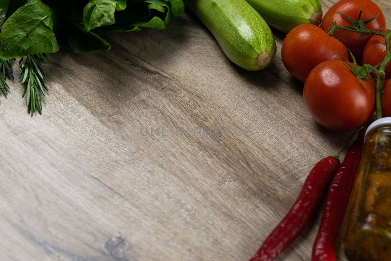 A dark bread sandwich ut in half with chicken, tomatoes, spinach, cheese and carrots stands on a wooden board that stands on a checkered white green towel. Top views