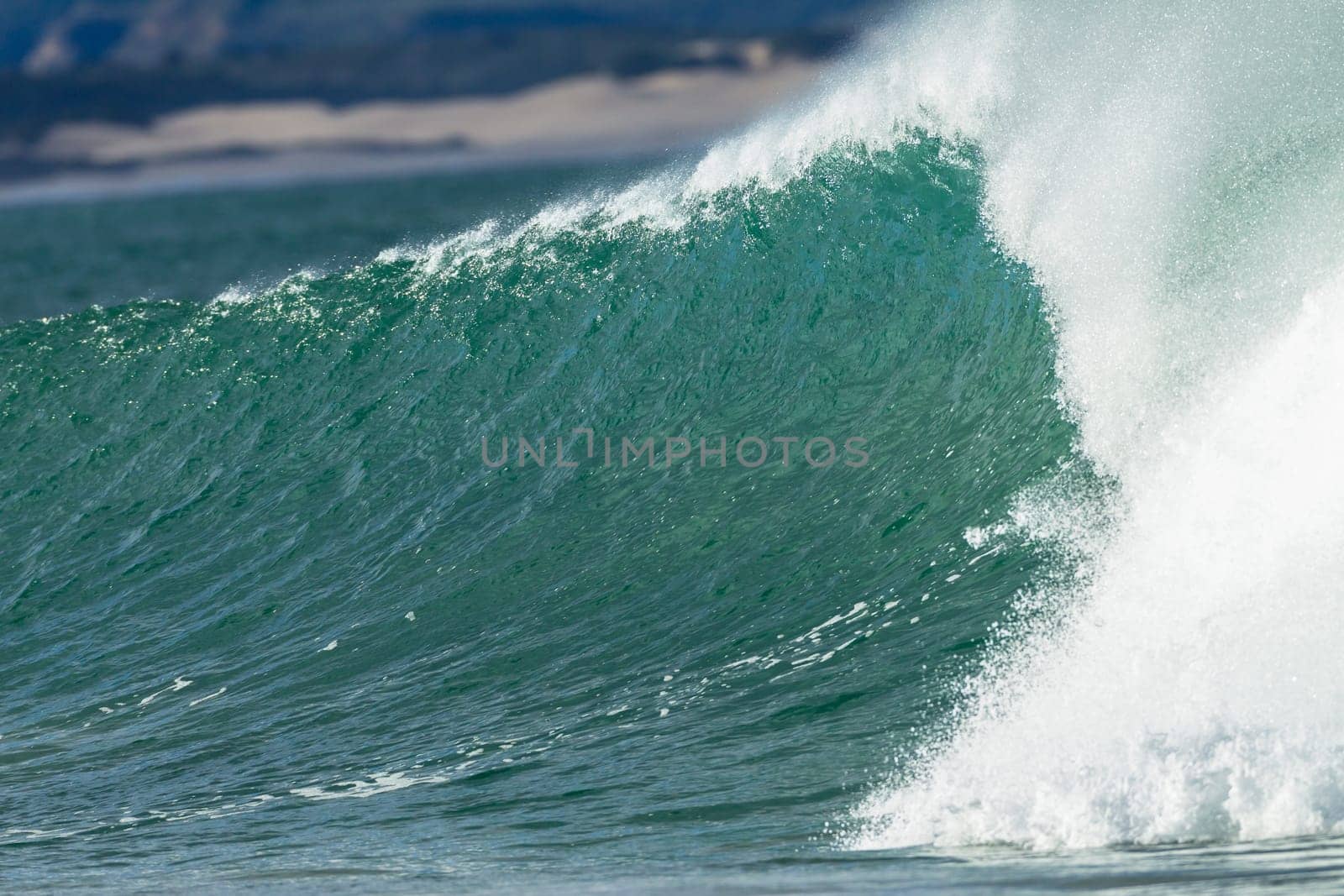 Ocean wave crashing along beach coastline with power energy