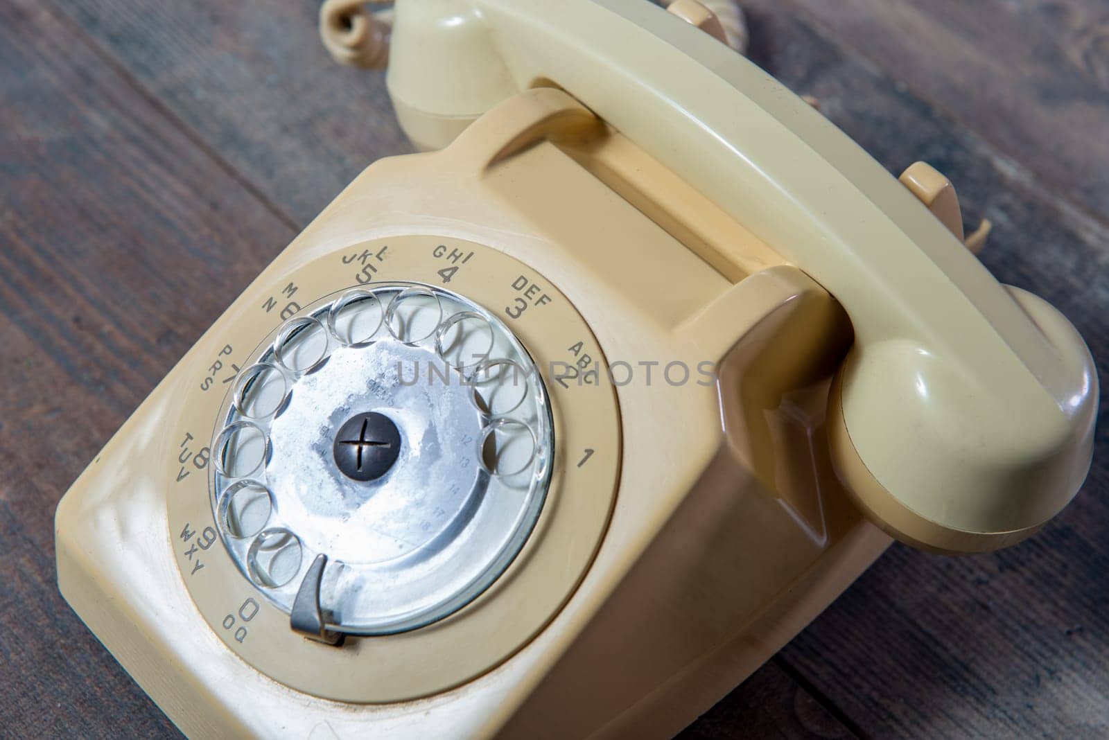 a beige old telephone on the wooden background