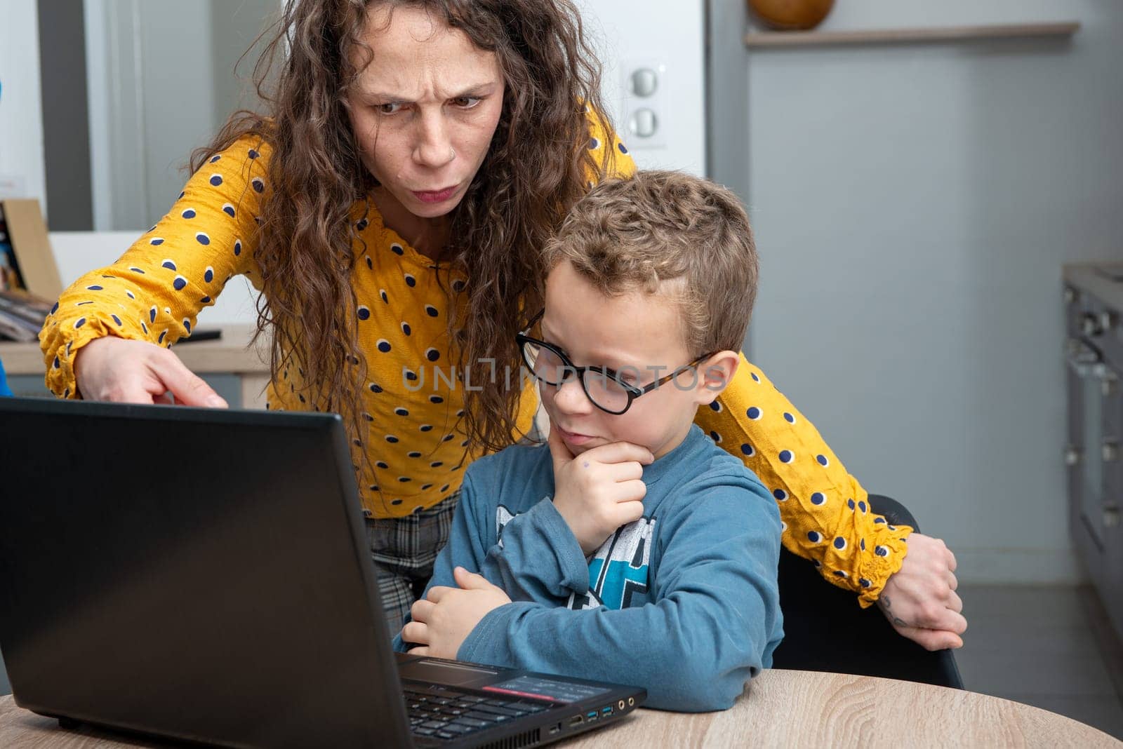 Mother and son using laptop in a kitchen at home