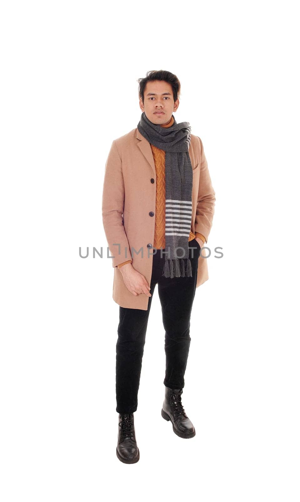 A tall young man standing in a beige coat in profile in the studio.looking at the camera, isolated for white background.