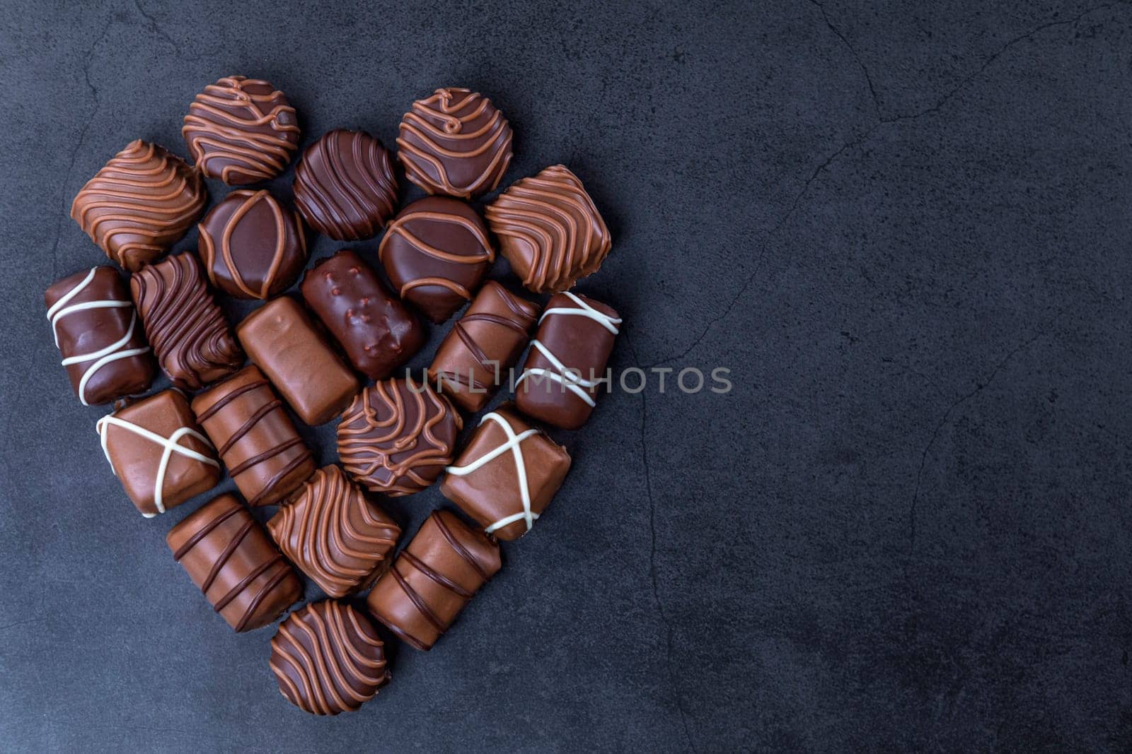 Stack of Chocolate candy in the shape of heart on a black background.  Focus on chocolate.