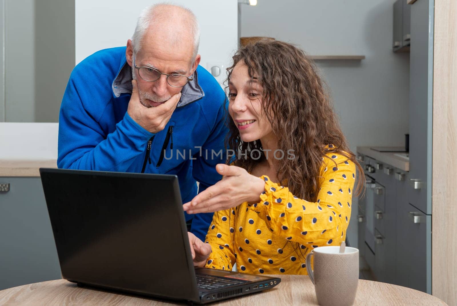 Young woman helps senior on a laptop computer