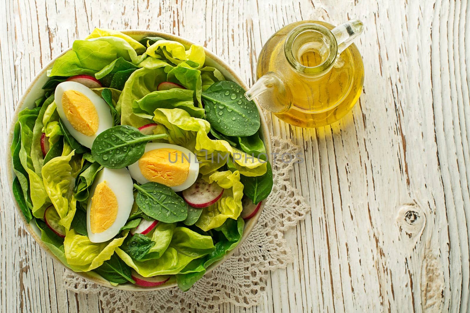 Healthy green salad with eggs on wooden table background. Healthy meal.