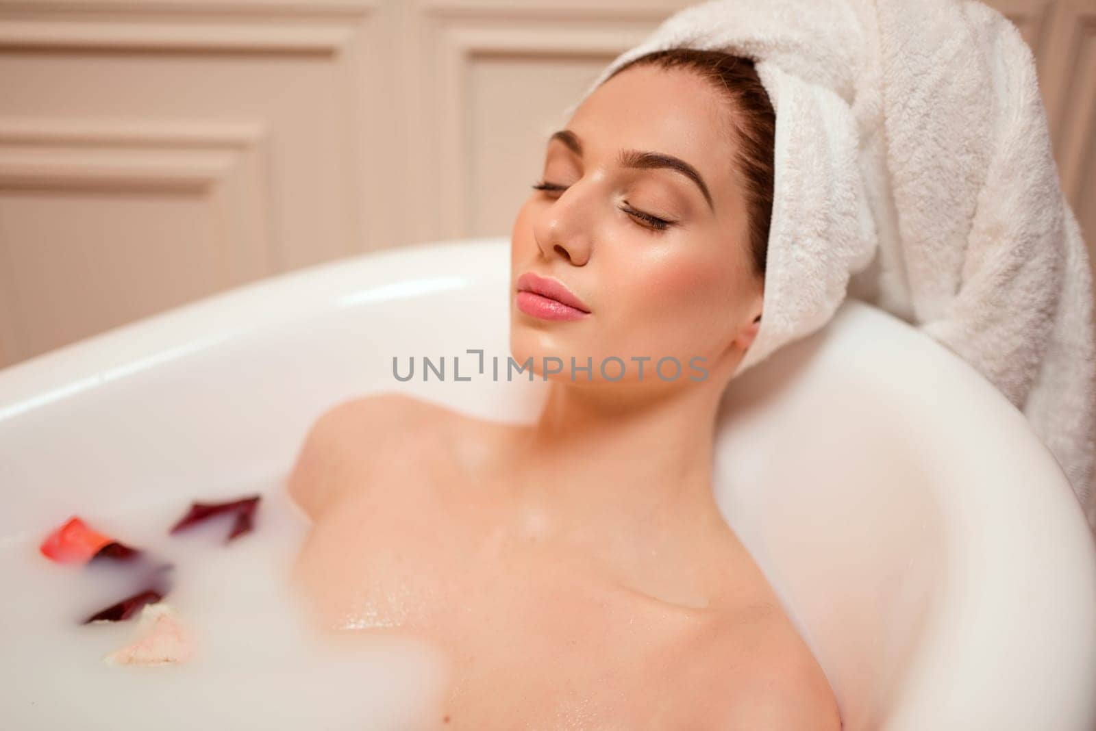 Beautiful woman in bathroom with rose petals.
