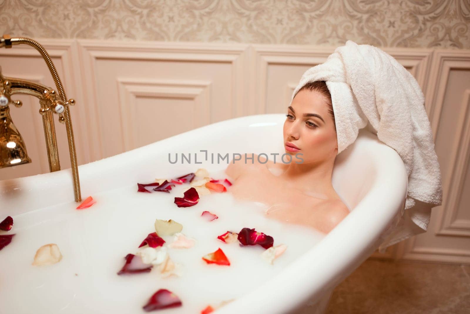 Beautiful woman in bathroom with rose petals.