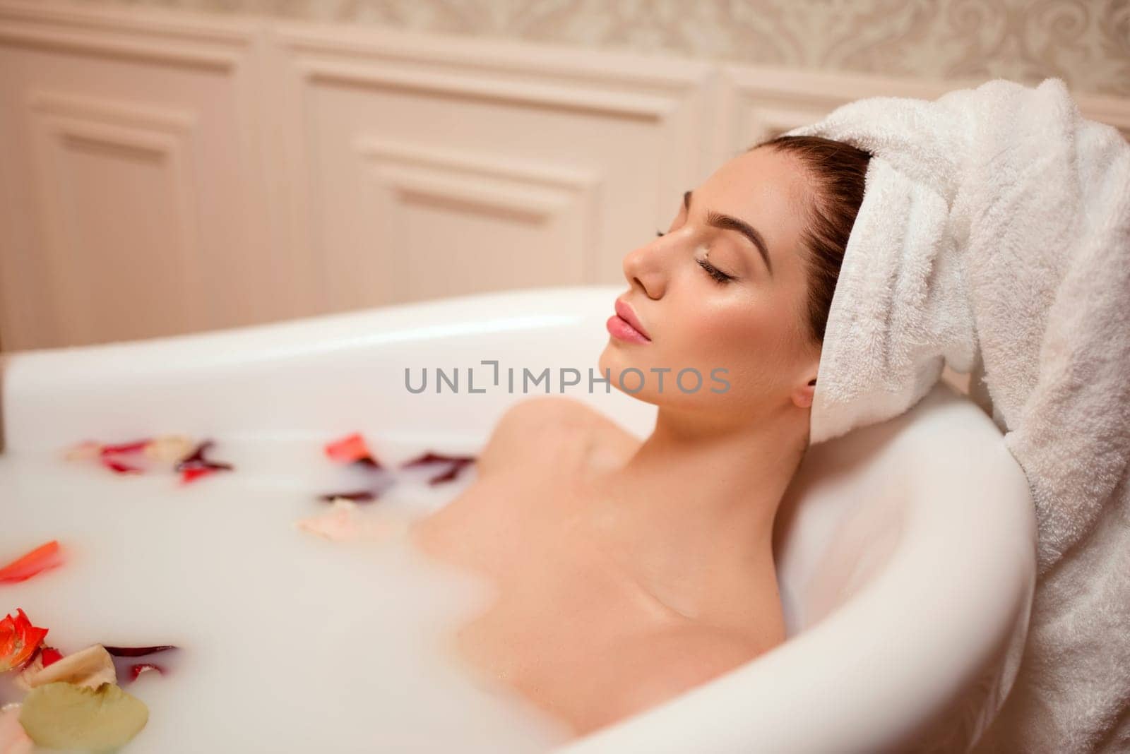 Beautiful woman in bathroom with rose petals and foam.