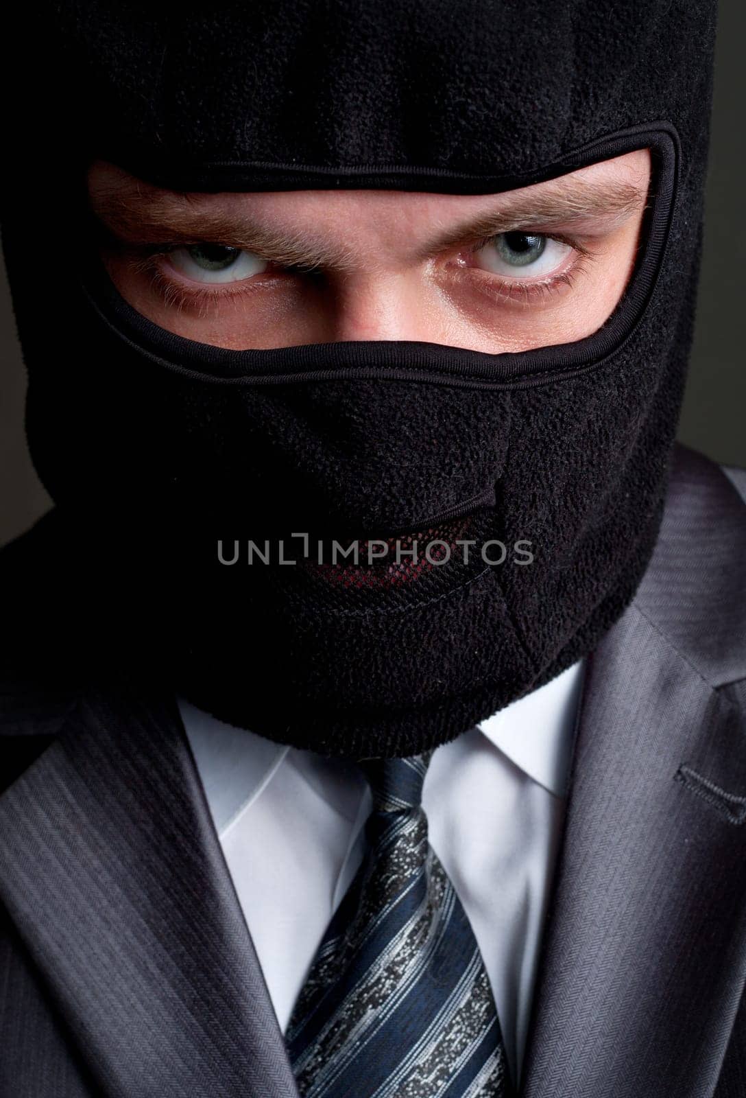 Business crime. Businessman in black balaclava looking to you