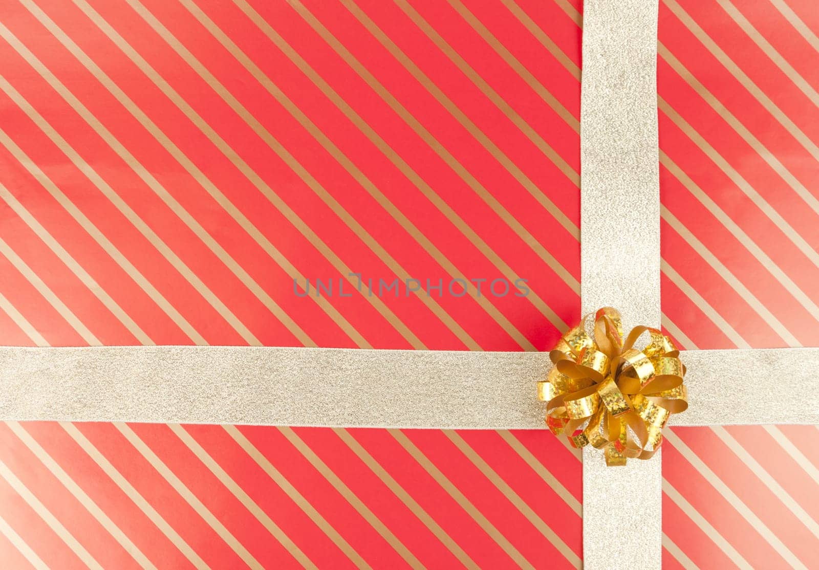 Gold ribbon and bow on striped red gift paper