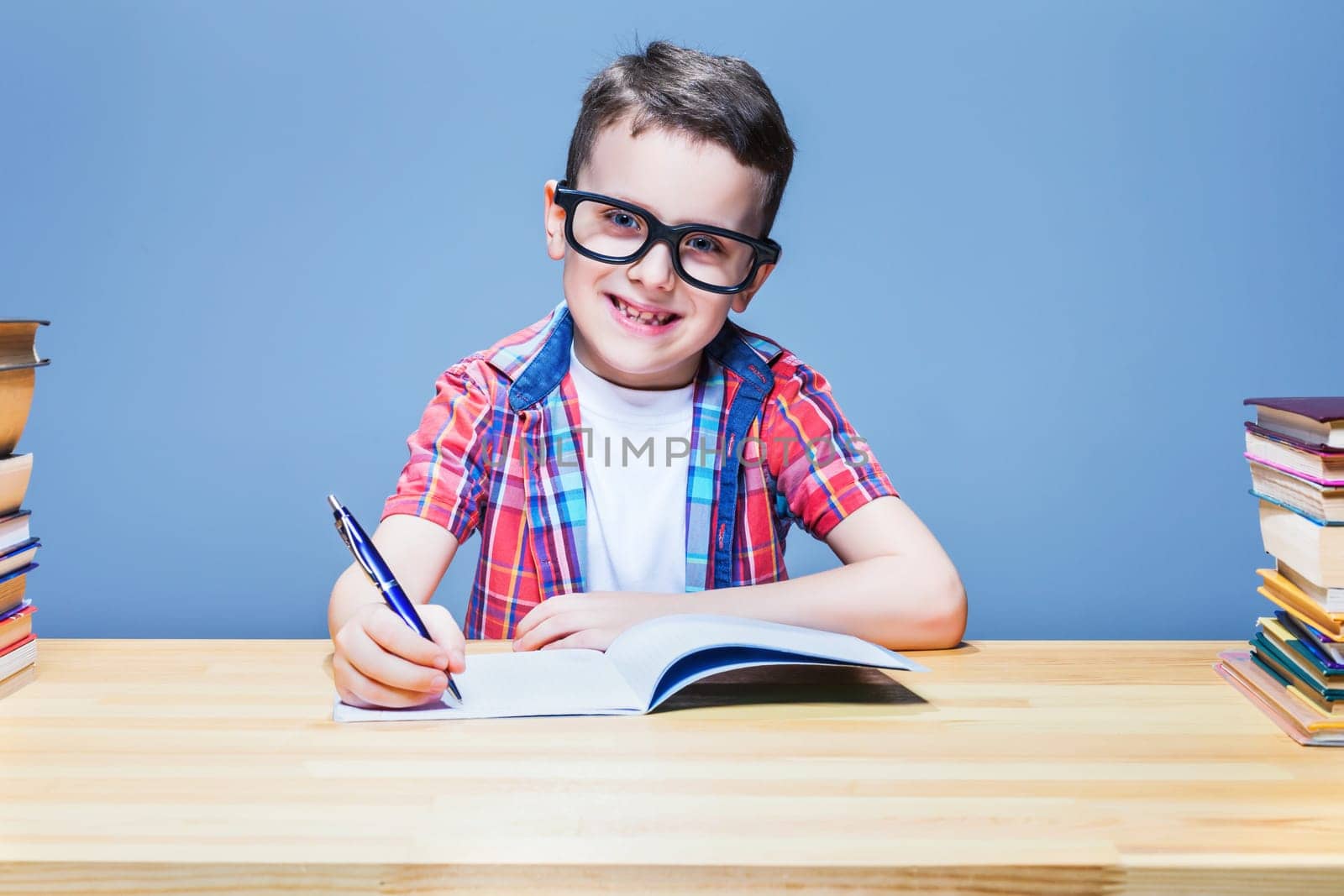 Young schoolboy learns homework, education concept. Pupil in glasses doing exercise in notebook