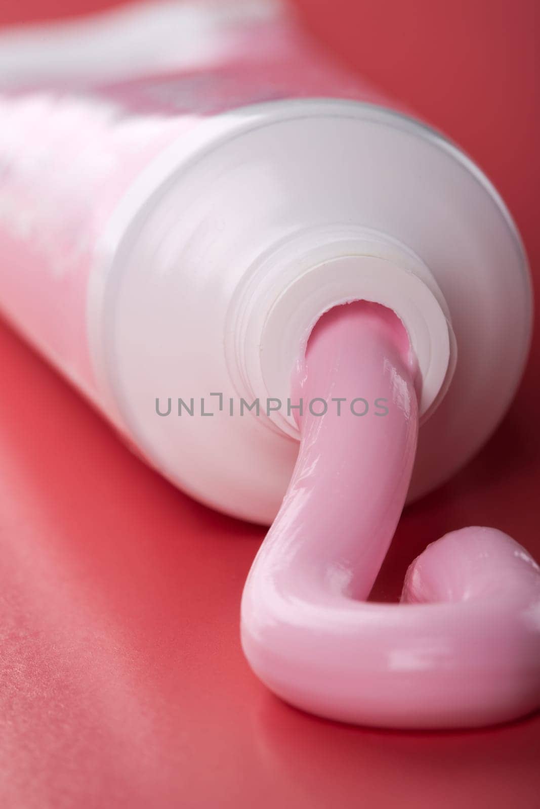 Pink toothpaste squeezing out of tube