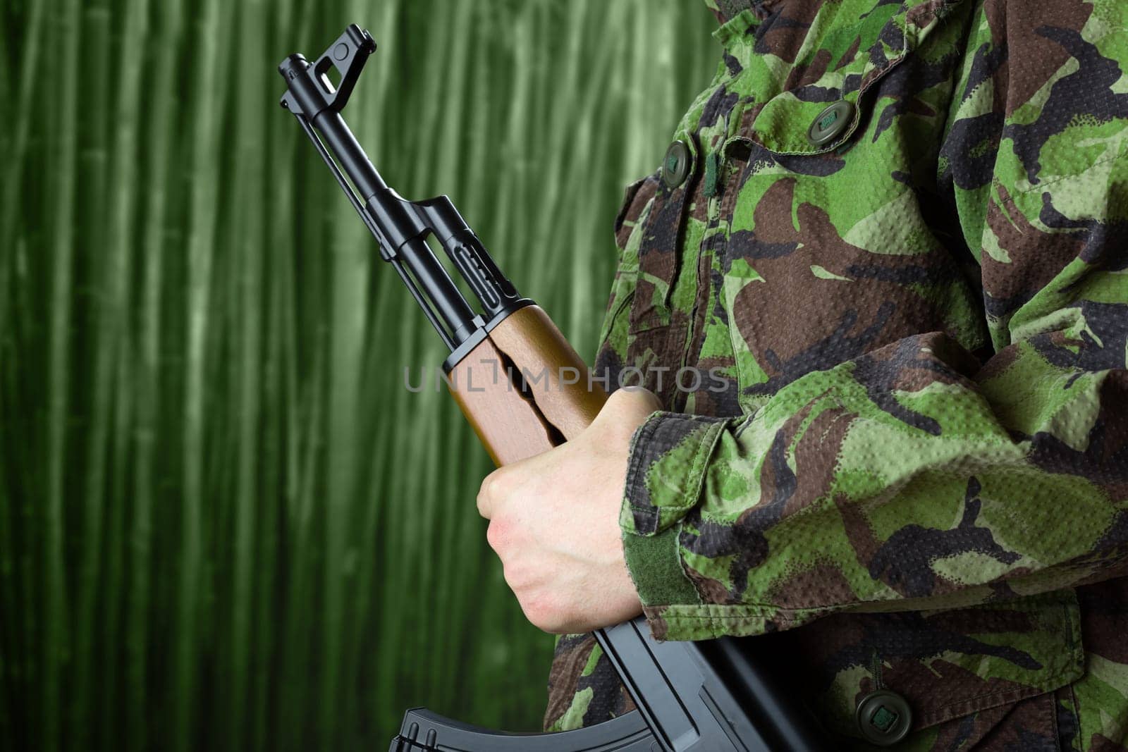 Soldier holding rifle AK-47 against jungle