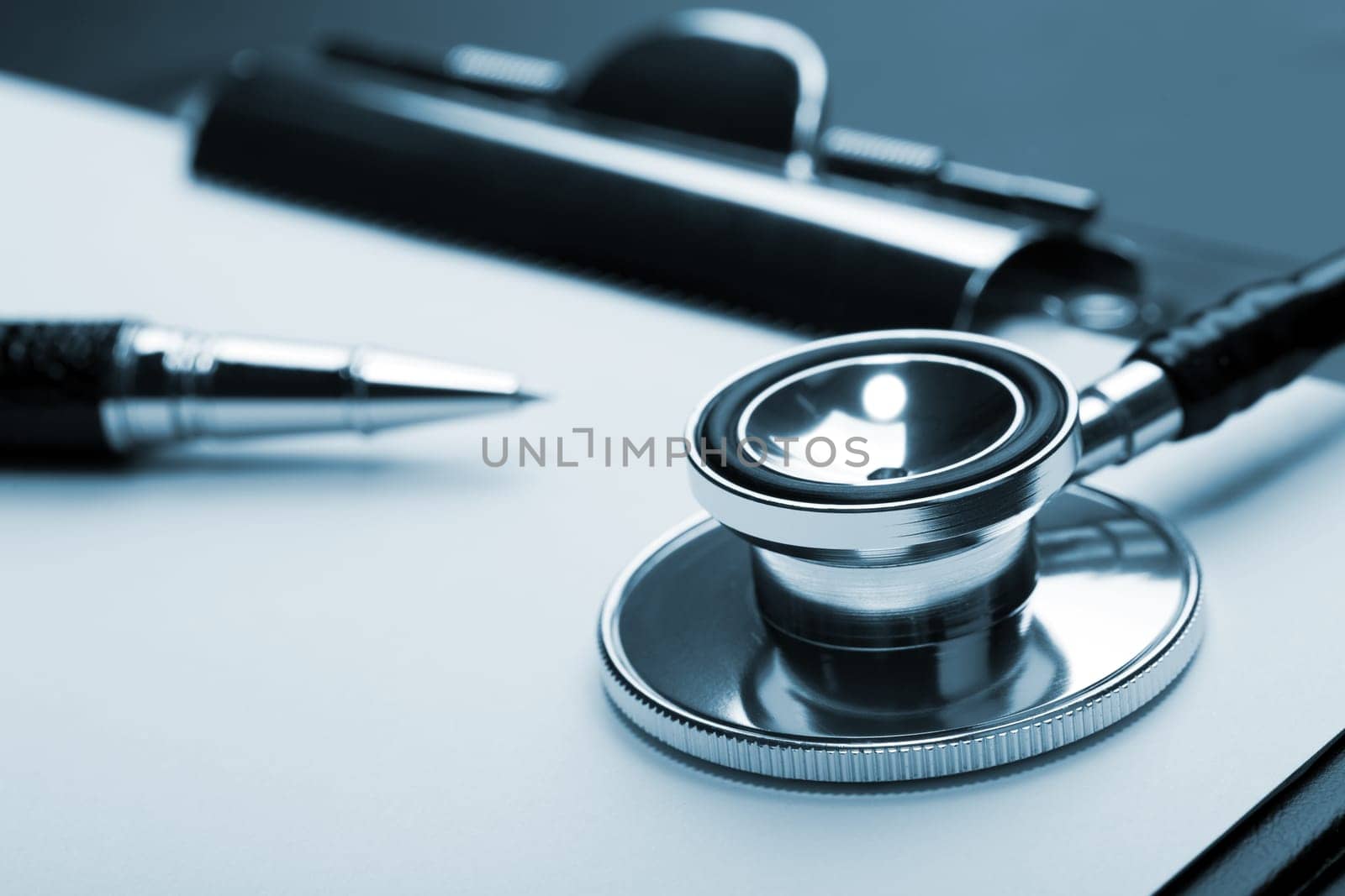 Closeup of medical stethoscope on clipboard. Toned in blue
