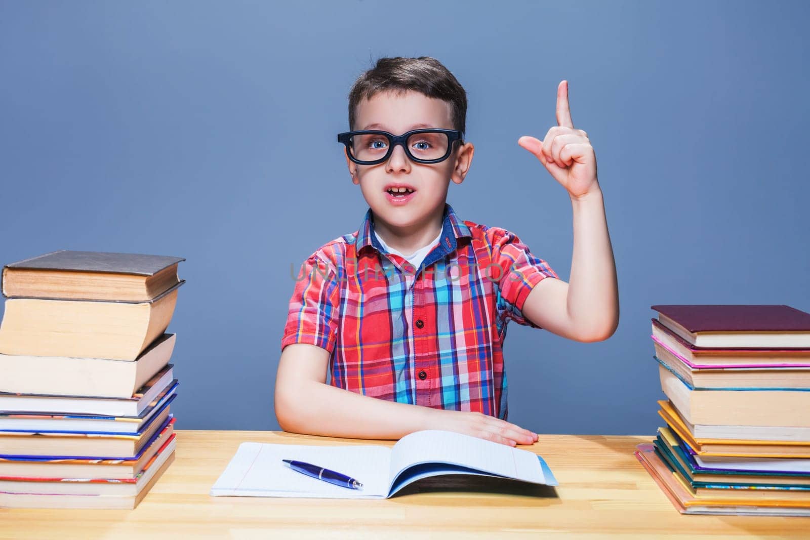Little schoolboy learns homework at the desk in classroom. Pupil in glasses gets knowledge