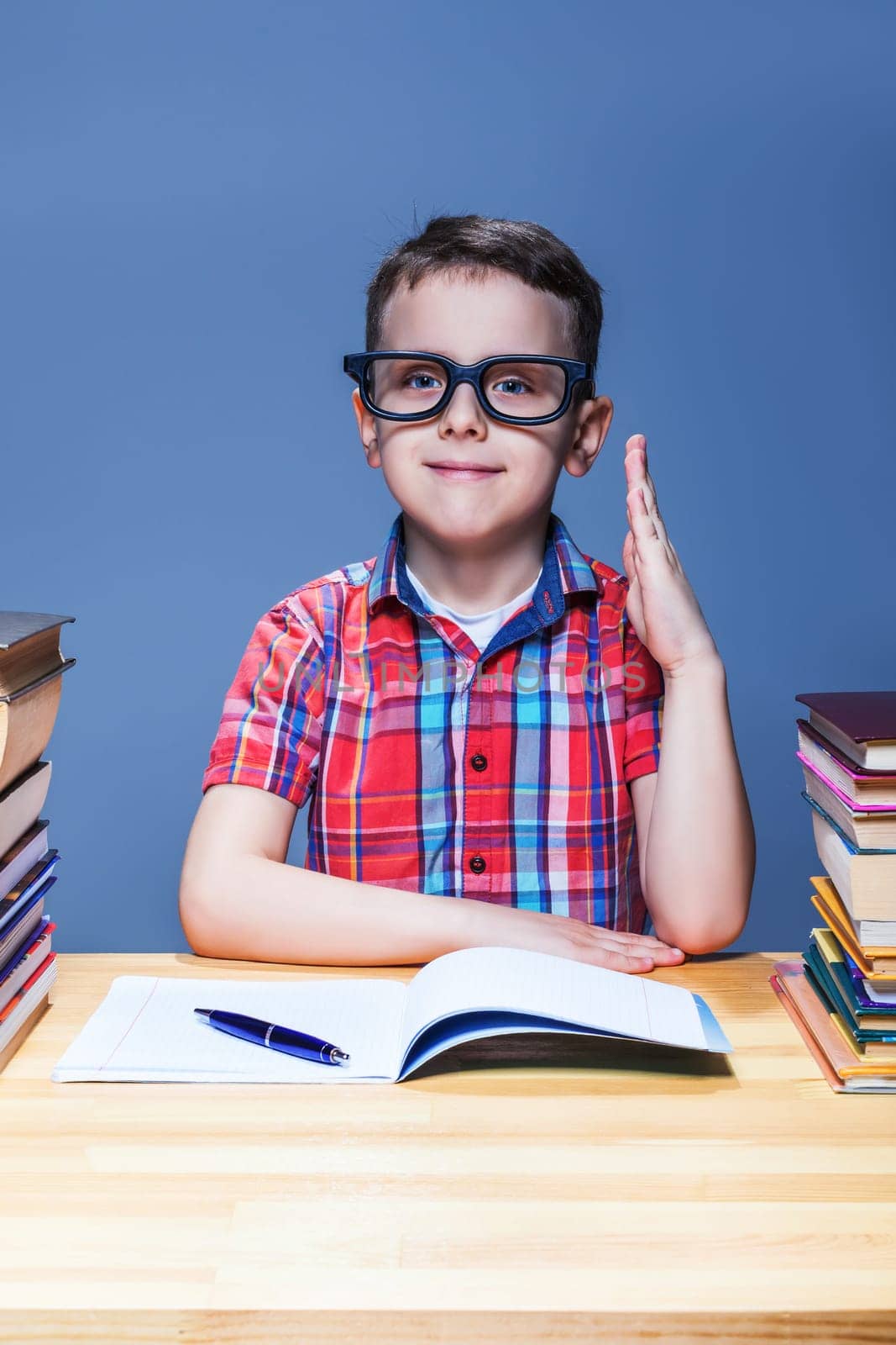 Little pupil pulls a hand up at the lesson in classroom. Education concept