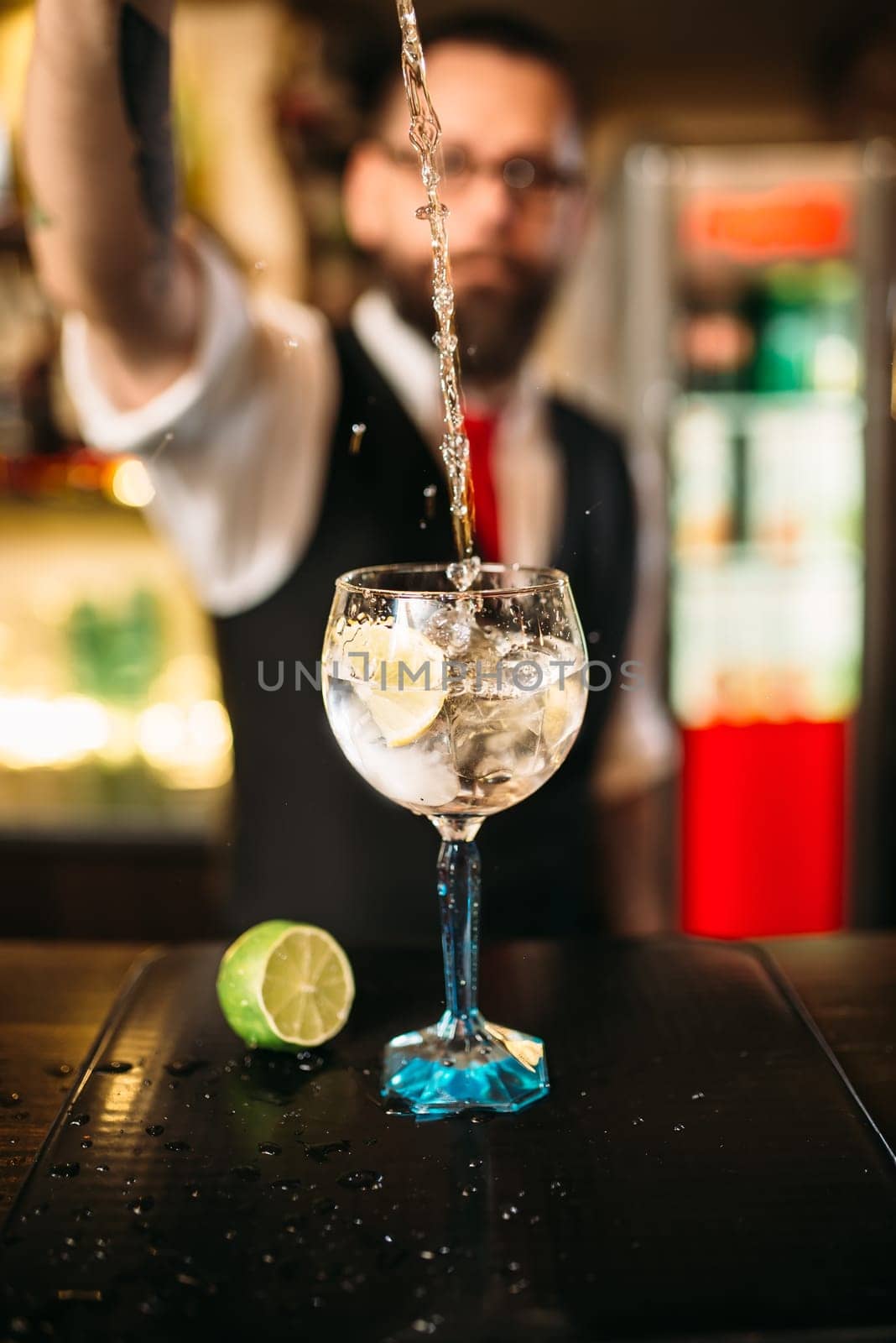 Bartender pouring alcoholic drink in glass. Barman flairing with alcoholic cocktail