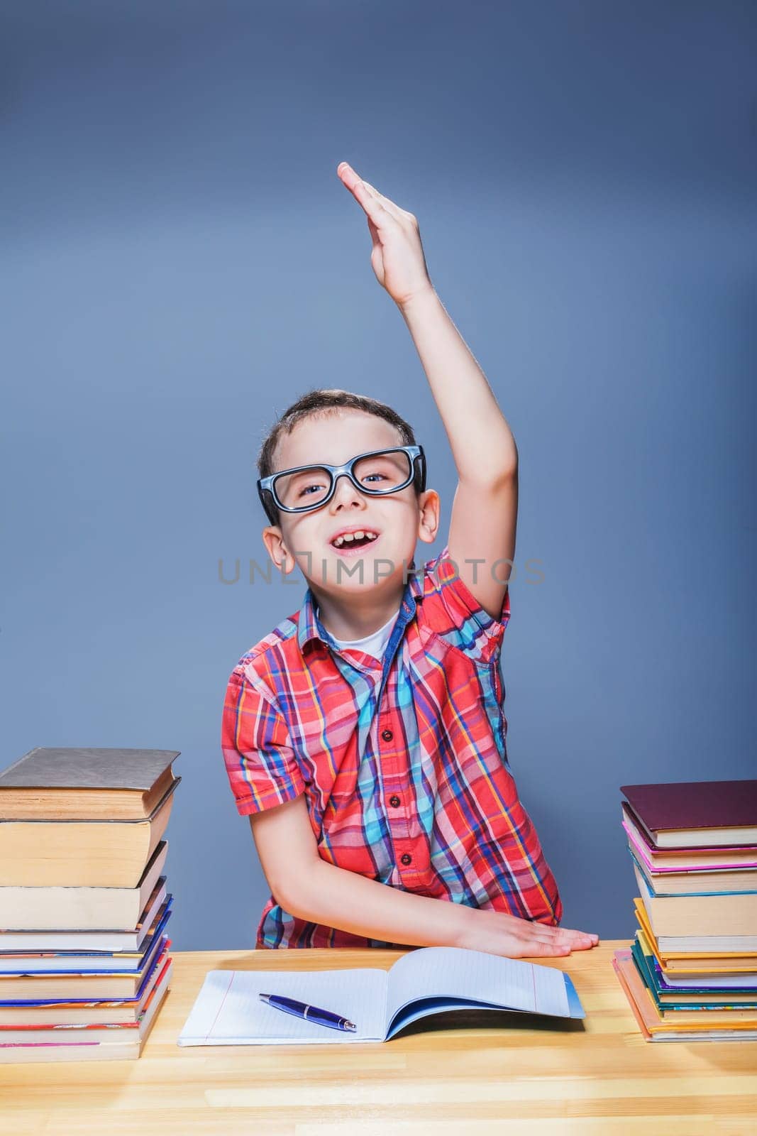 Little pupil pulls a hand up at the lesson in classroom. Education concept