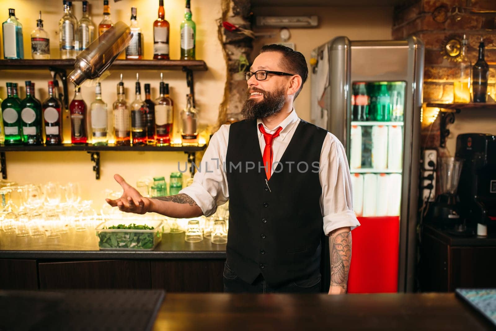Bartender with shaker show trick behind a bar counter. Modern club nightlife