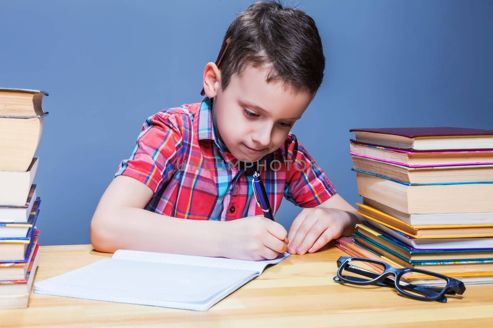 Pensive schoolboy study at school, homework learning. Pupil in glasses against books