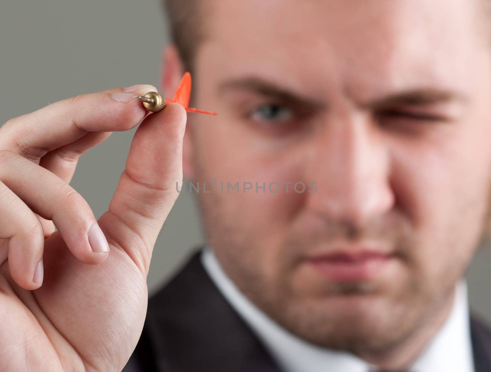 Business games - young businessman aiming by dart