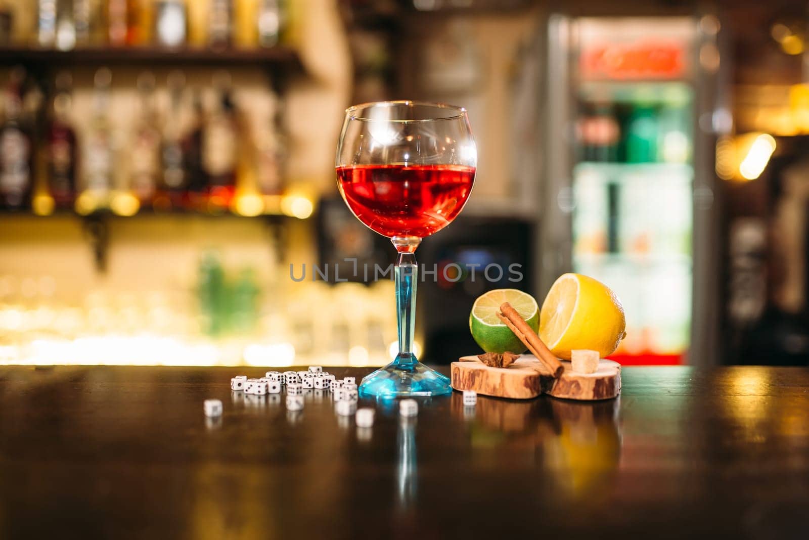 Beverage in glass, lime, lemon, salt and dice on wooden bar counter