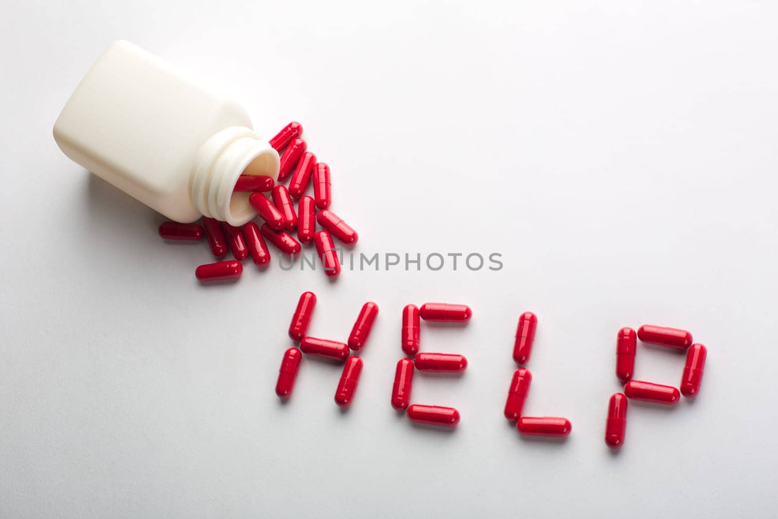 Pills spilling from an open bottle in HELP word