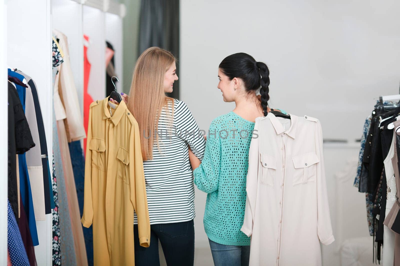 Women standing back hold dresses in the shop