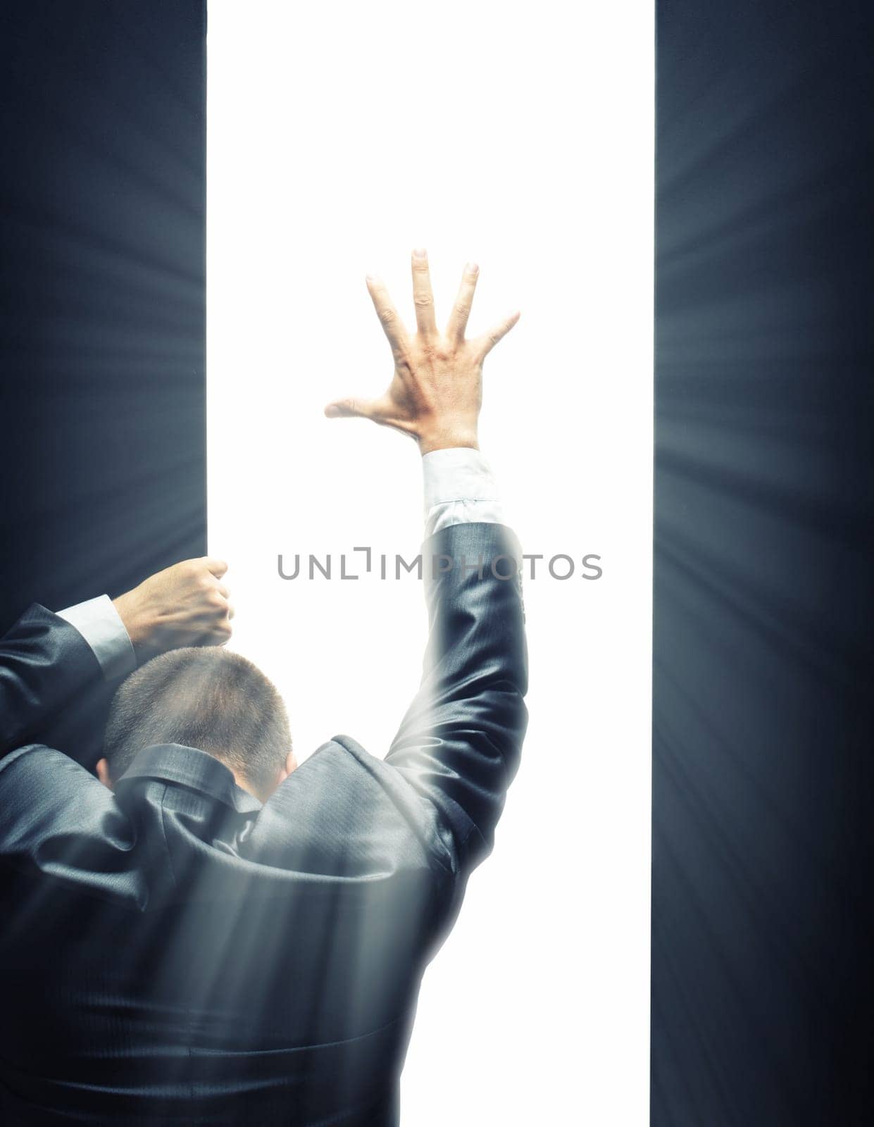 Businessman opening some gate and reaching hand to a bright light