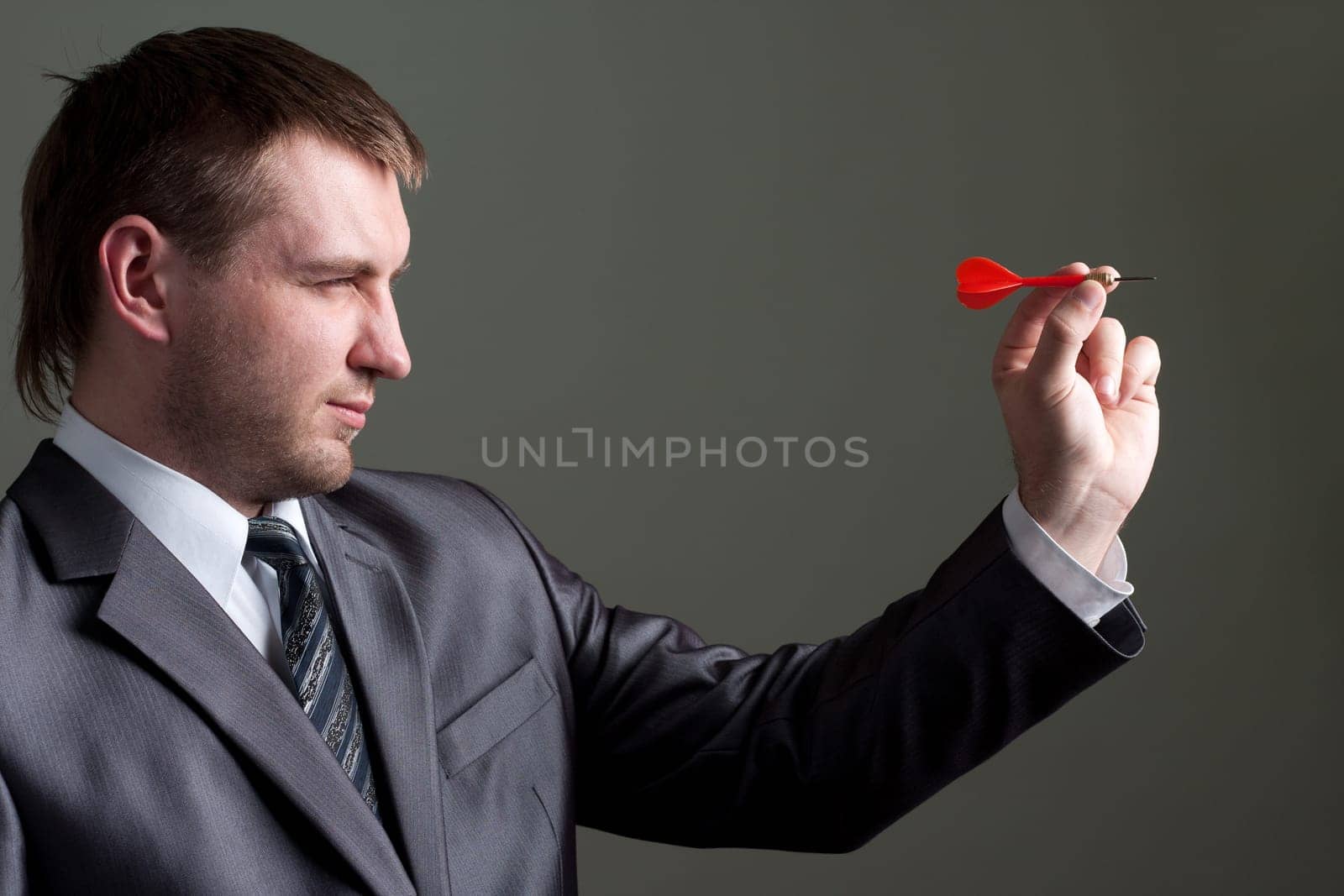 Business games - young businessman aiming by dart