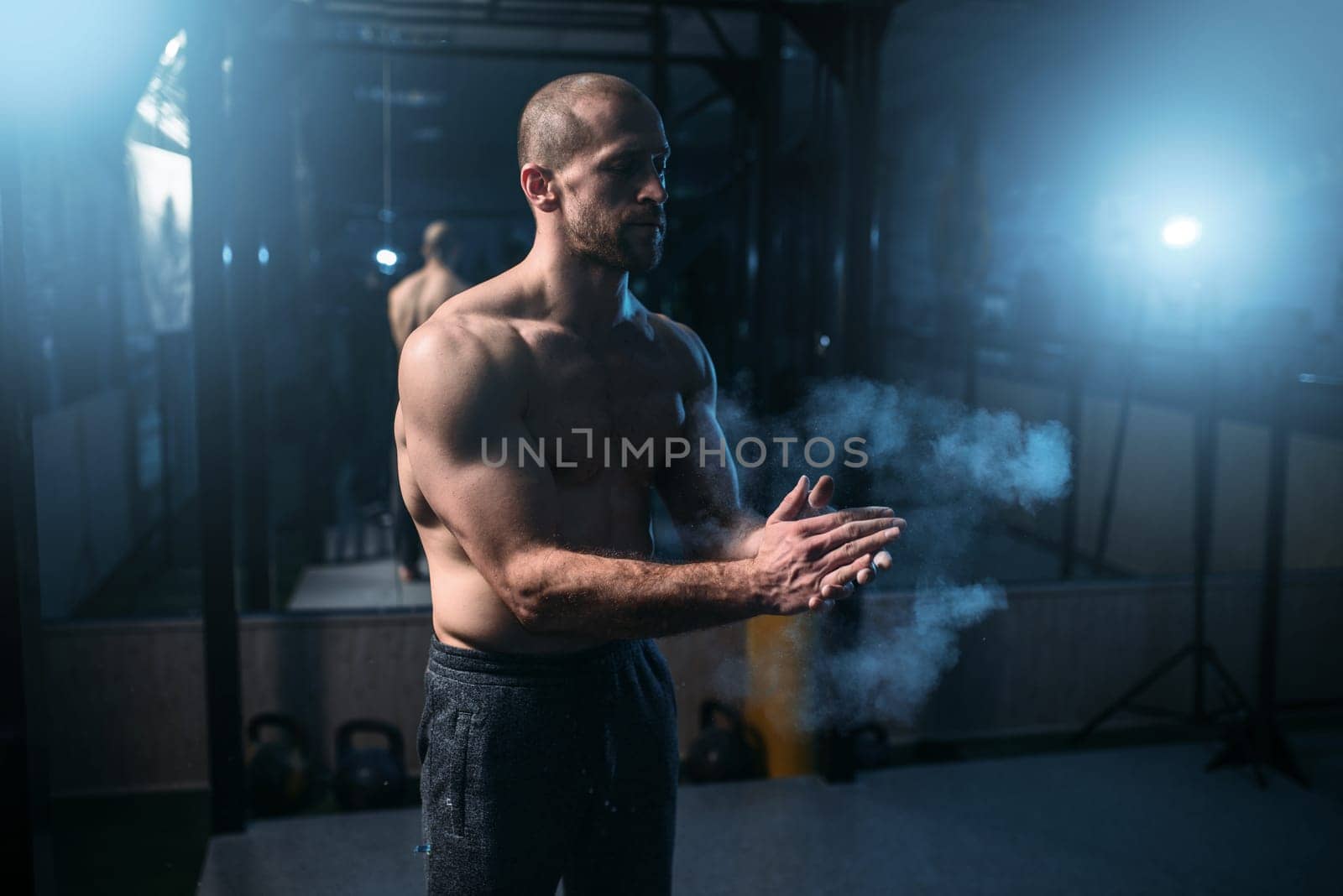 Male athlete rubs hands with talcum powder. Gymnast prepare for exercises, rubbing talc