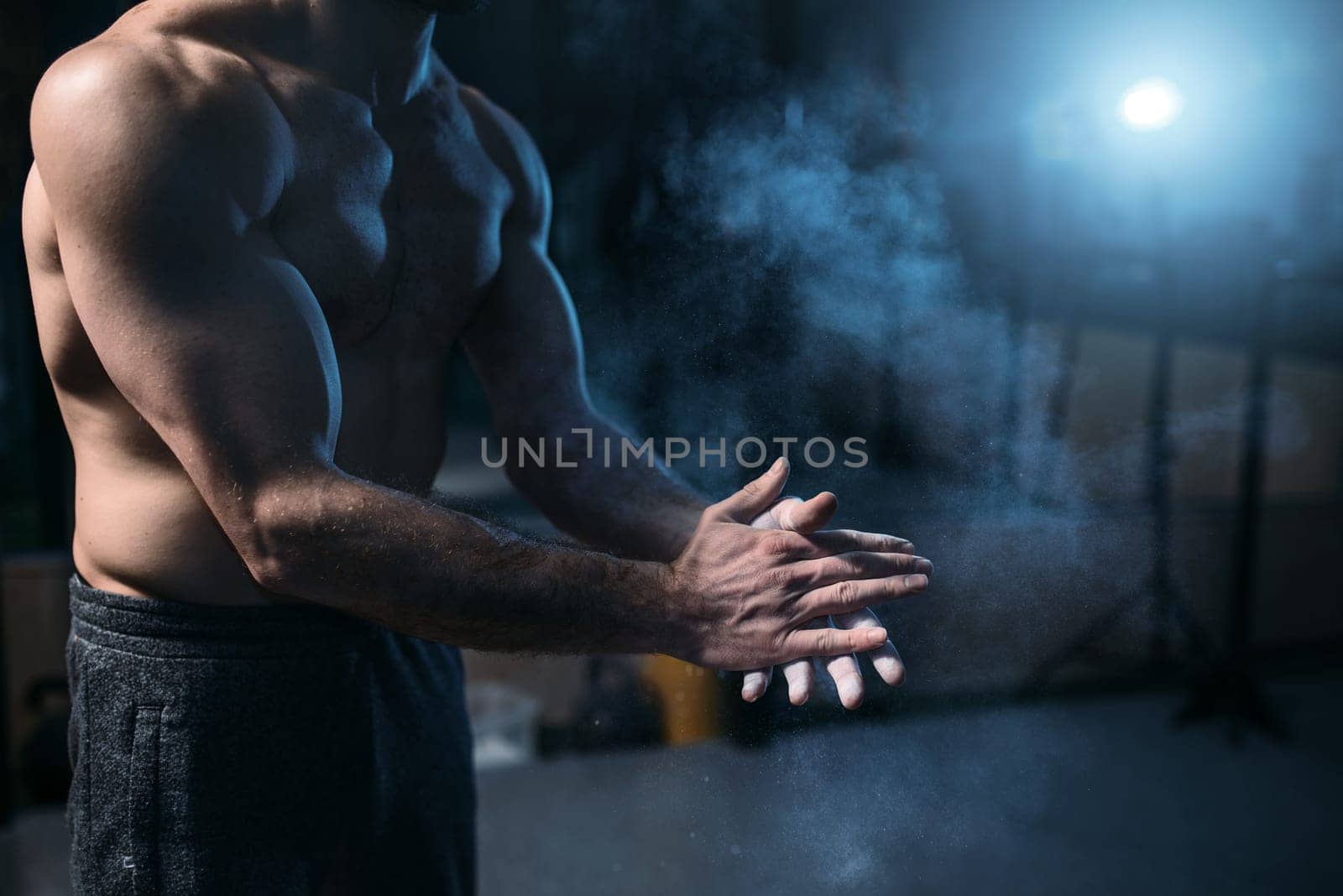 Male athlete rubs hands with talcum powder. Gymnast prepare for exercises, rubbing talc