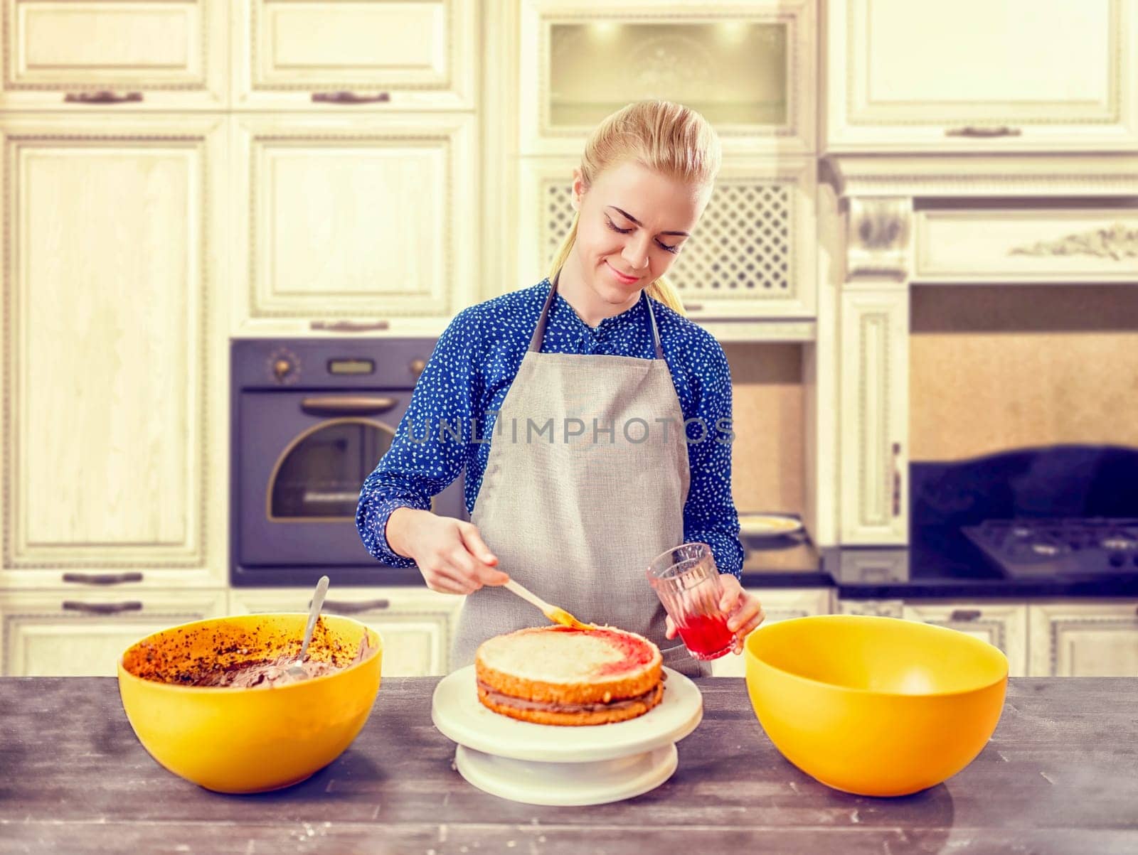Woman cook smears baked cake with berry jam. Tasty dessert homemade cooking