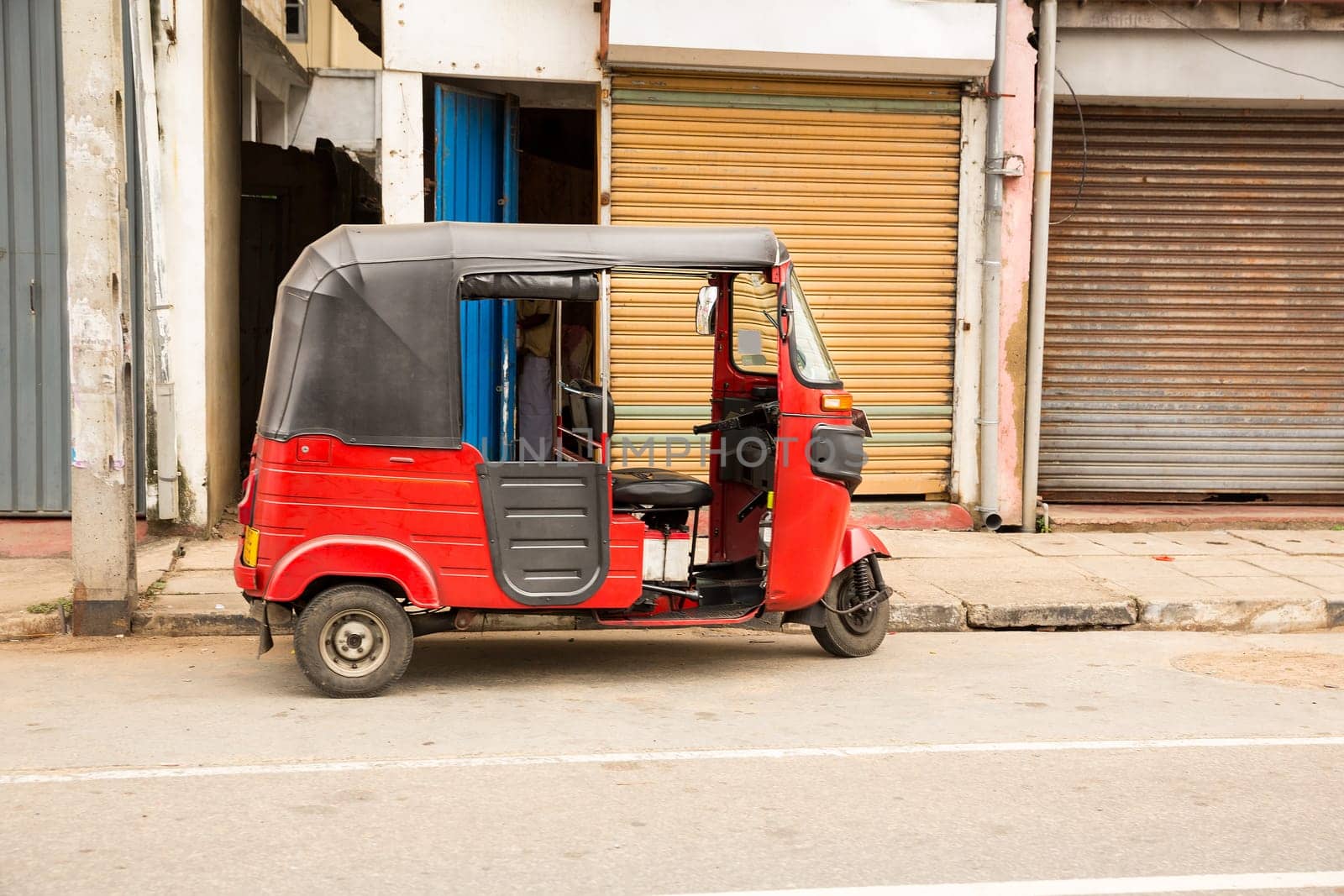 Tuk-tuk on road of Sri Lanka, side view. Ceylon traditional tourist transport, local taxi