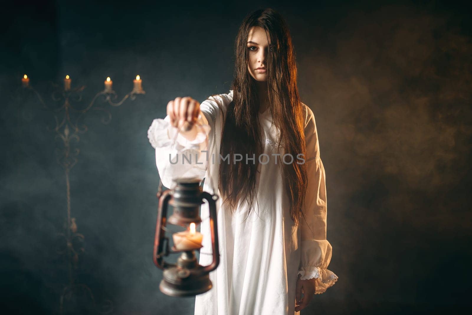 Female person in white shirt holds kerosene lamp in hand. Dark magic ritual, occult and exorcism