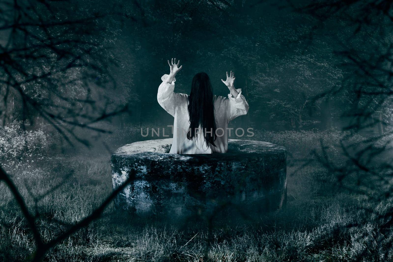 Witch in white shirt gets out of an abandoned well in the night. Dark magic, occultism and exorcism, witchcraft