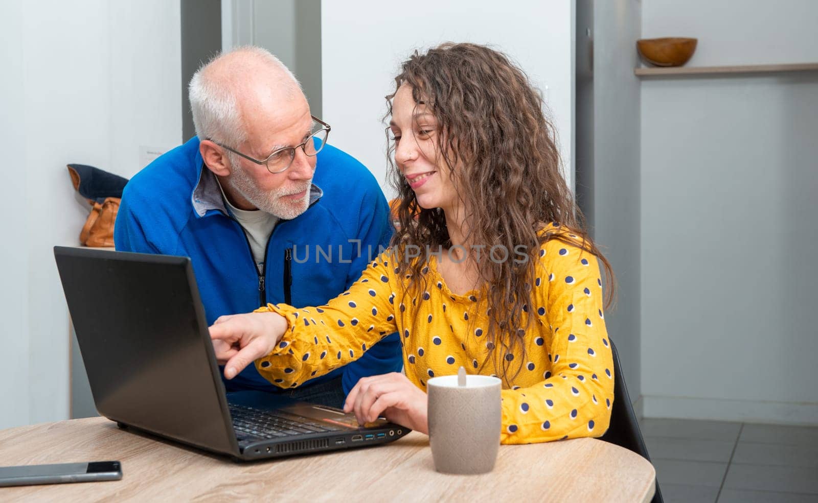 Young woman helps senior on a laptop computer