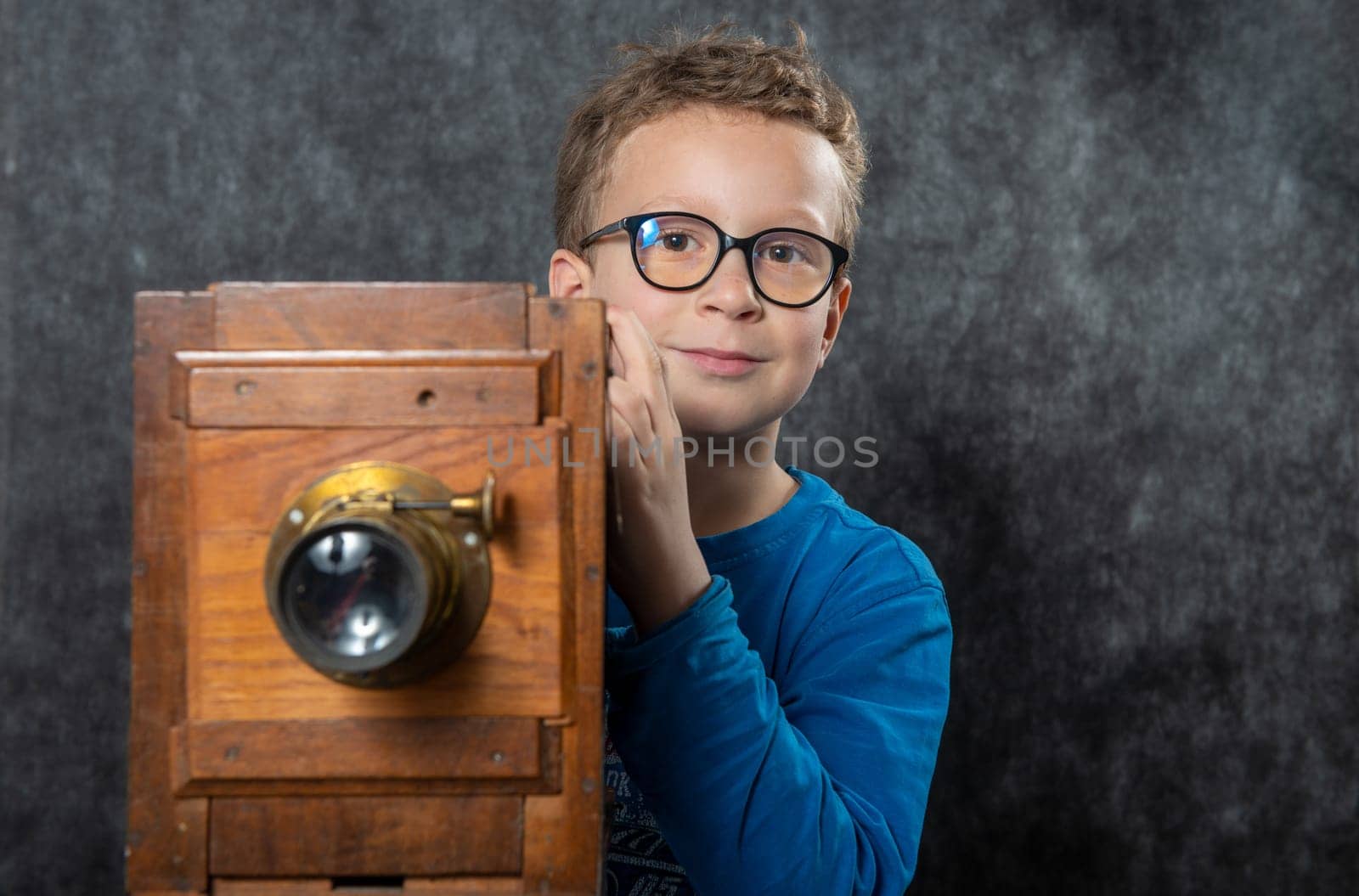 cheerful boy retro photographer with a vintage wooden camera