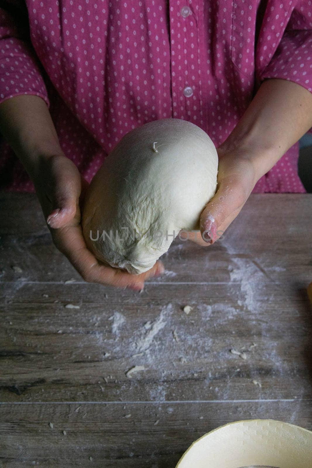 Women's hands mix the dough on a wooden table. Preparing bread for baking. Front views