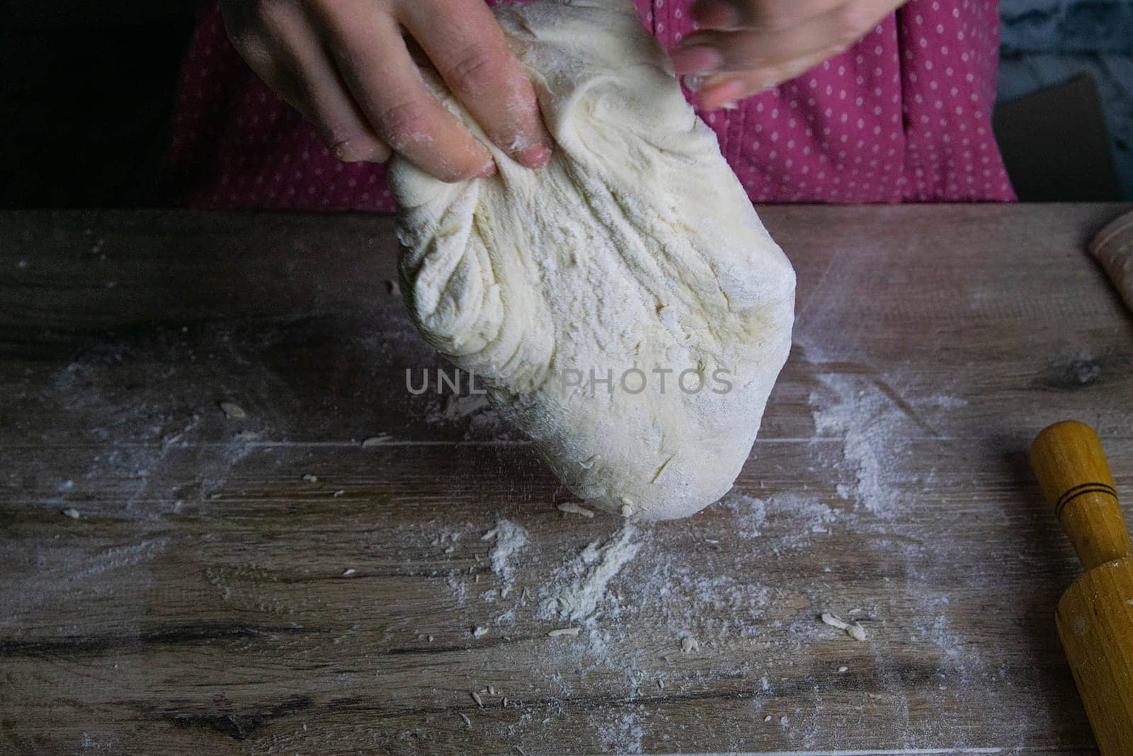 Women's hands mix the dough on a wooden table. Preparing bread for baking. Front views