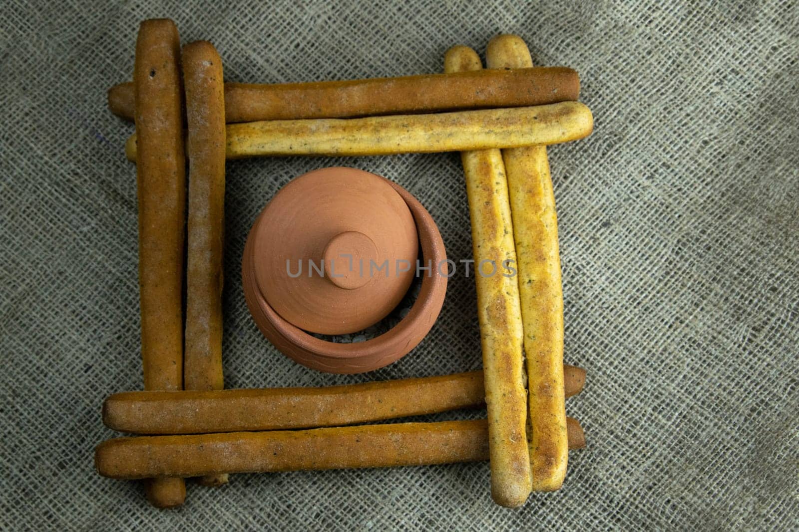 A pile of breadsticks or grissini in the shape of a square, inside an open glacier. Top views