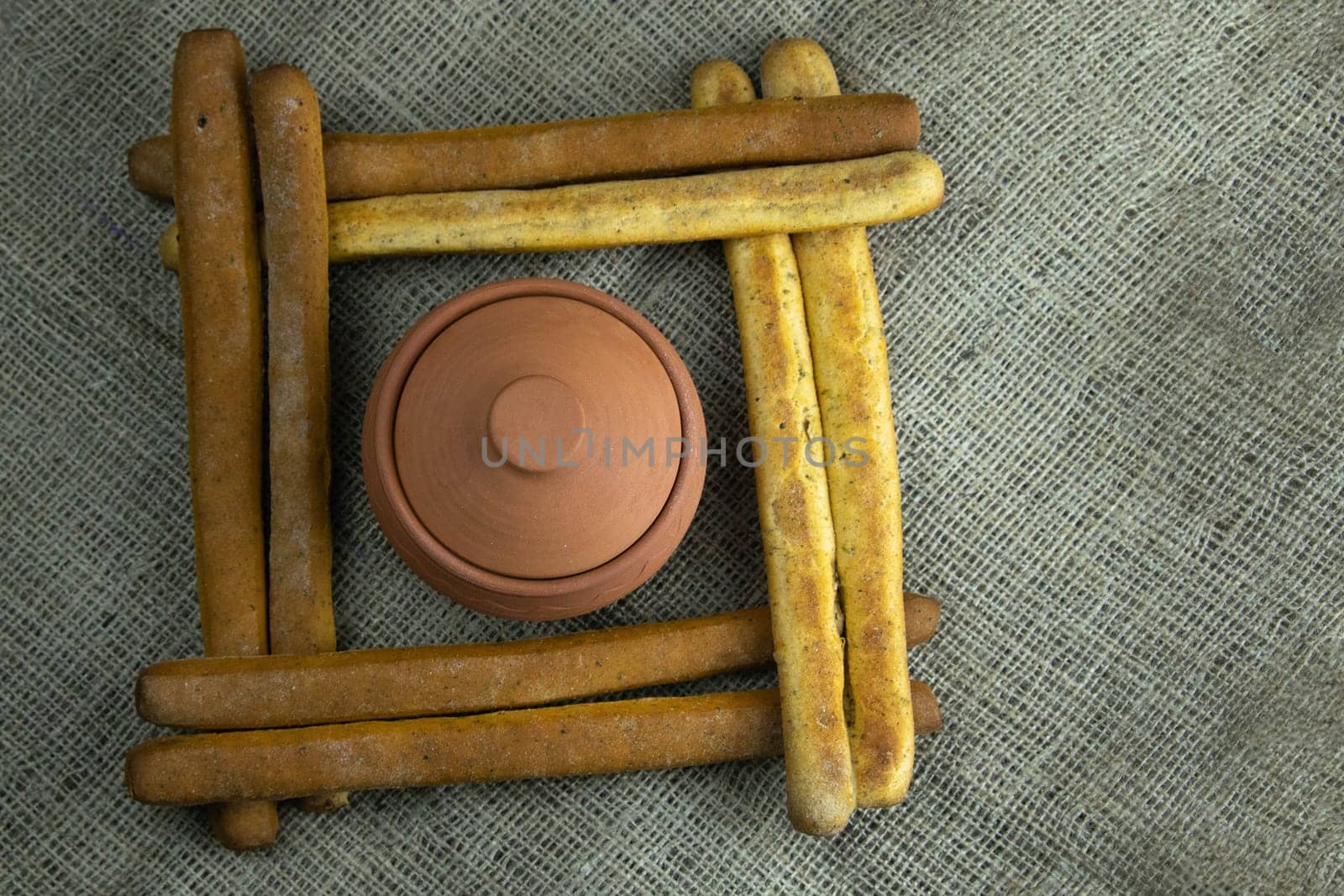 A pile of breadsticks or grissini in the shape of a square, inside an open glacier. Top views