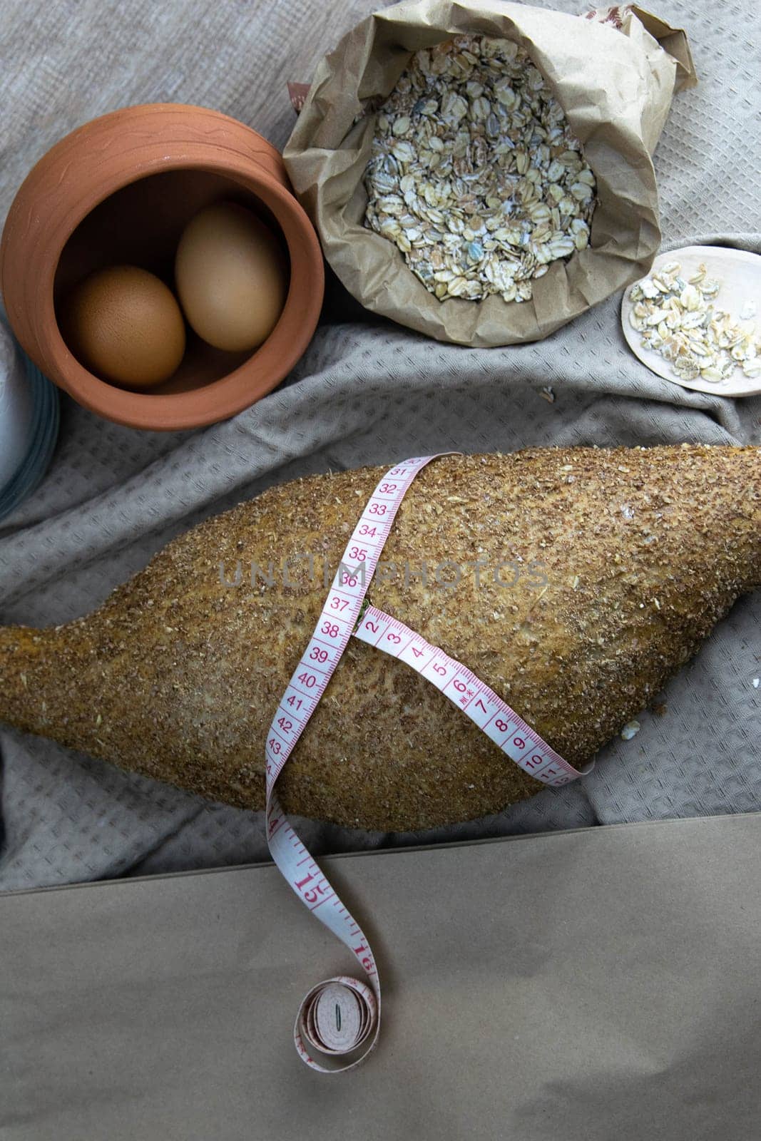 Concept shot of spice bread sticks with a wooden spoon on the wood table, oatmeal and a skein of bag thread, egg, flour, seeds and nuts. Front views