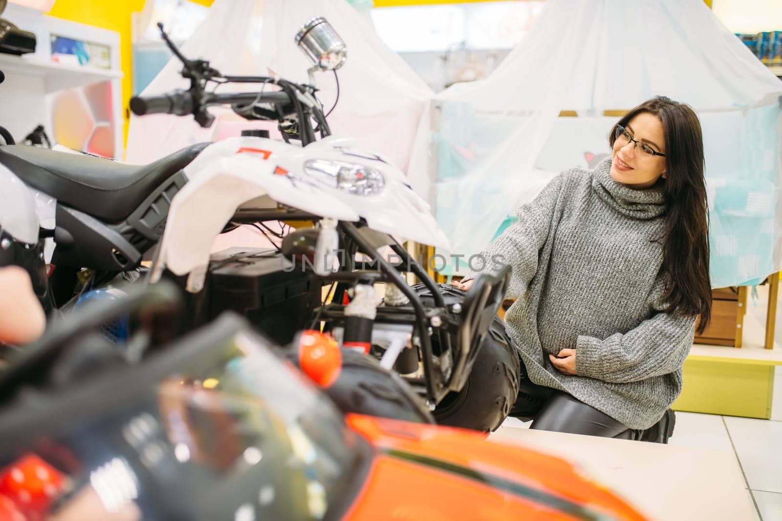 Pregnant woman choosing electric car in toy store, nobody. Toyshop interior, motor automobile for children