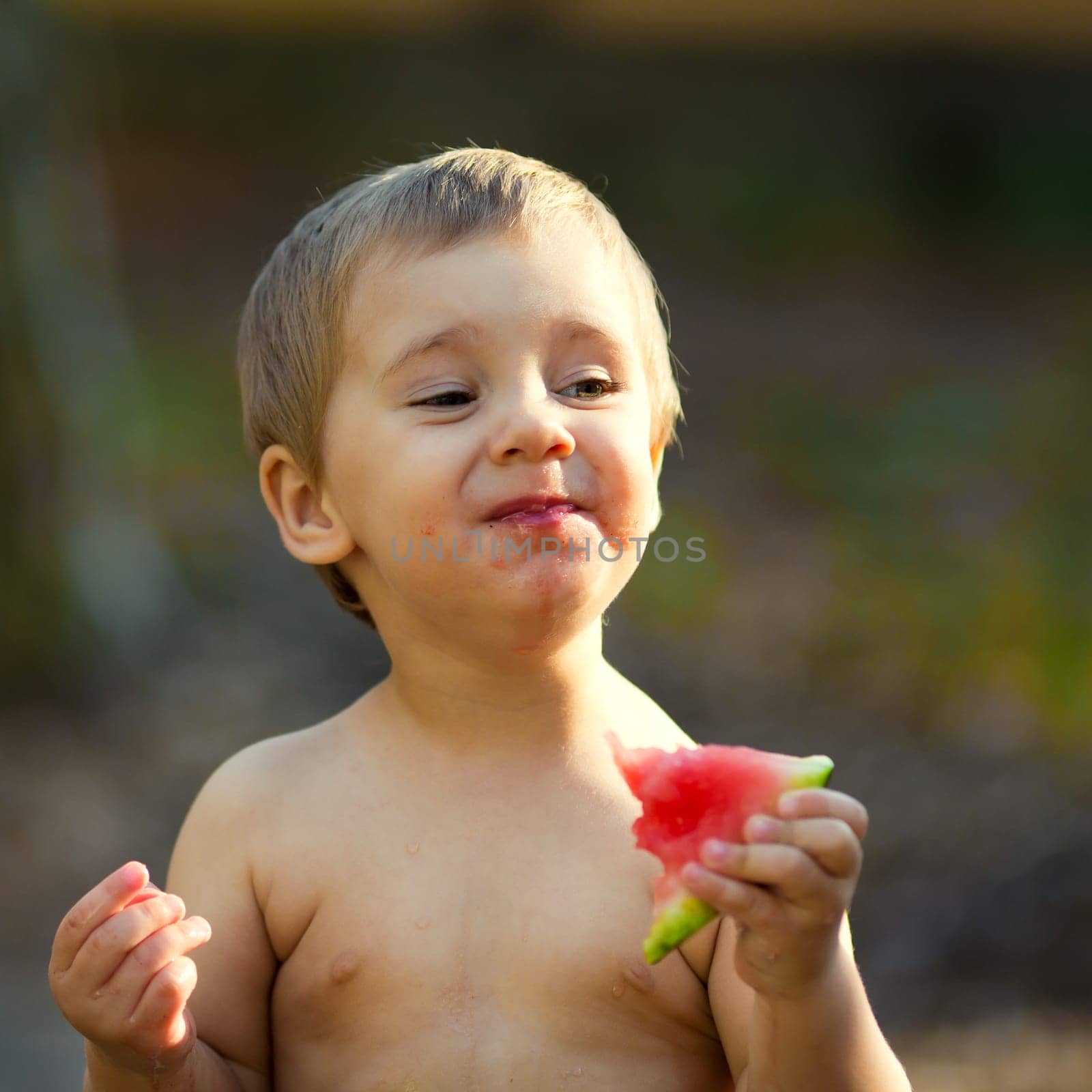 Happy child eating watermelon outdoors in summer