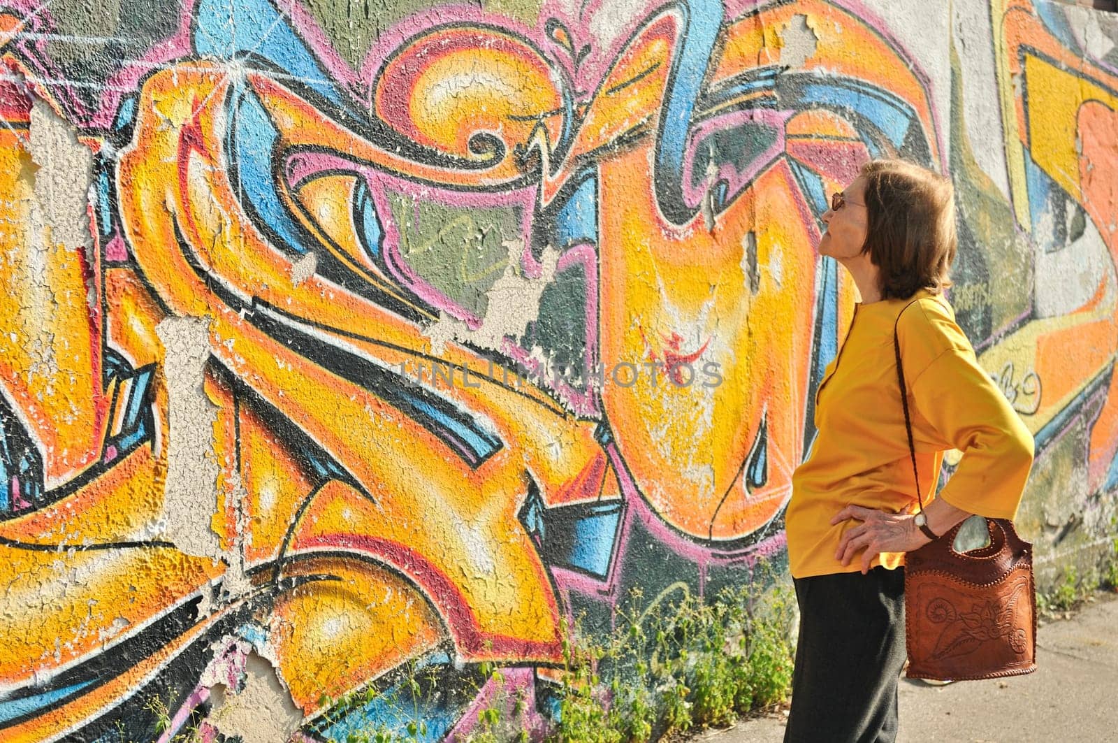 Senior woman looking at colourful graffiti wall
