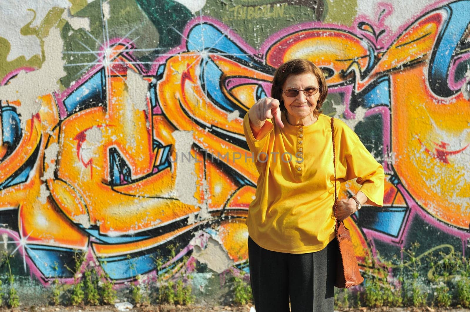 Senior woman standing at colourful graffiti wall